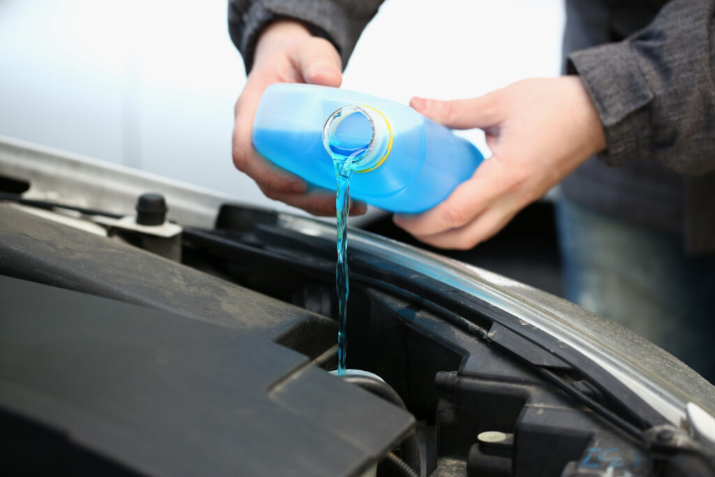 Auto technician pouring blue car wiper liquid to car